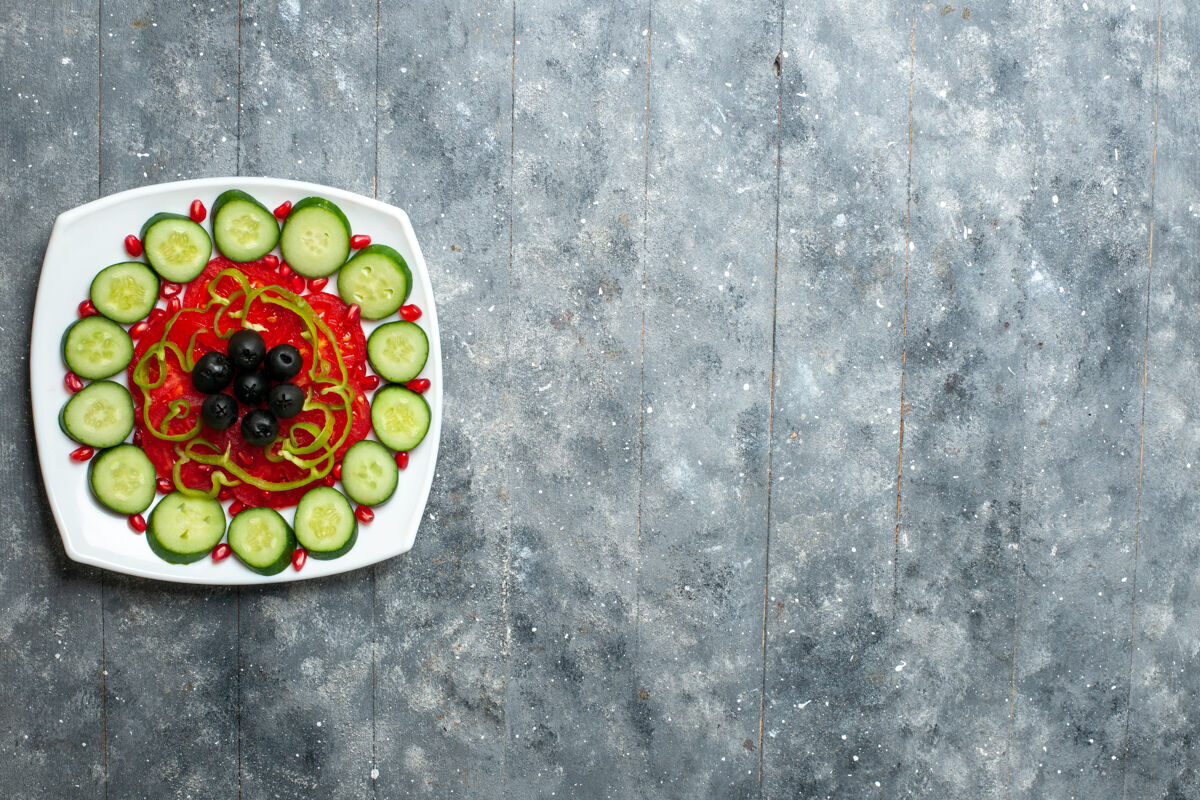 食物顶视图切片黄瓜和橄榄在灰色的乡村办公桌沙拉蔬菜维生素健康饮食盘中传统乡村橄榄