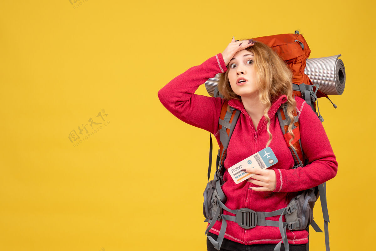时尚戴着医用面罩手持车票的年轻忧心忡忡 情绪激动的旅行女孩的正面图脸持有人