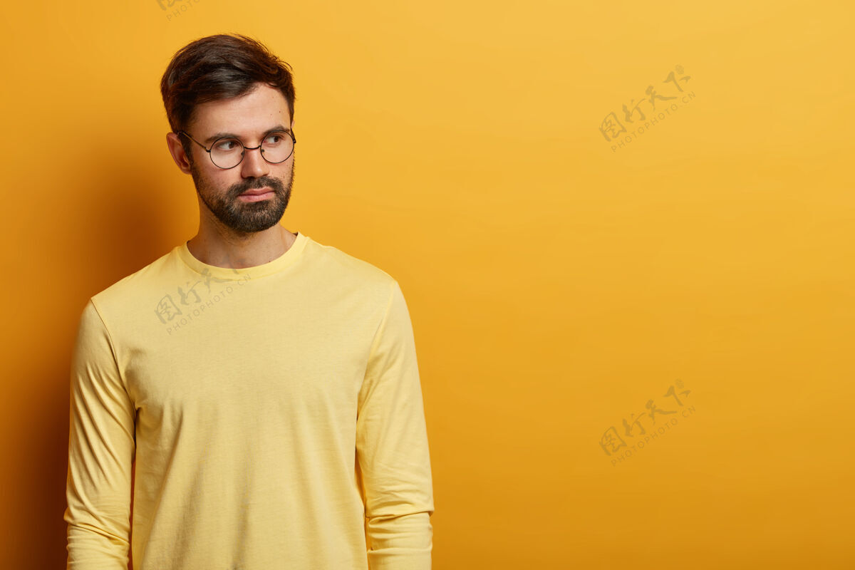 个人愁眉苦脸的欧洲男人镜头深思熟虑 戴着圆眼镜和休闲的黄色毛衣 为广告内容复制空间 思考思路 有冷静的表情青少年思想未刮胡子