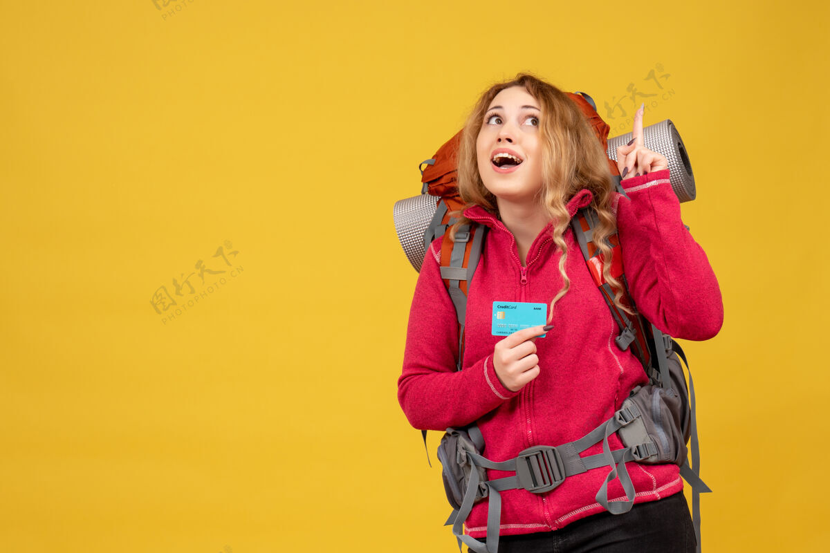 人正面图：戴着医用面罩微笑的年轻旅行女孩 拿着银行卡 正拿着行李漂亮成人年轻人