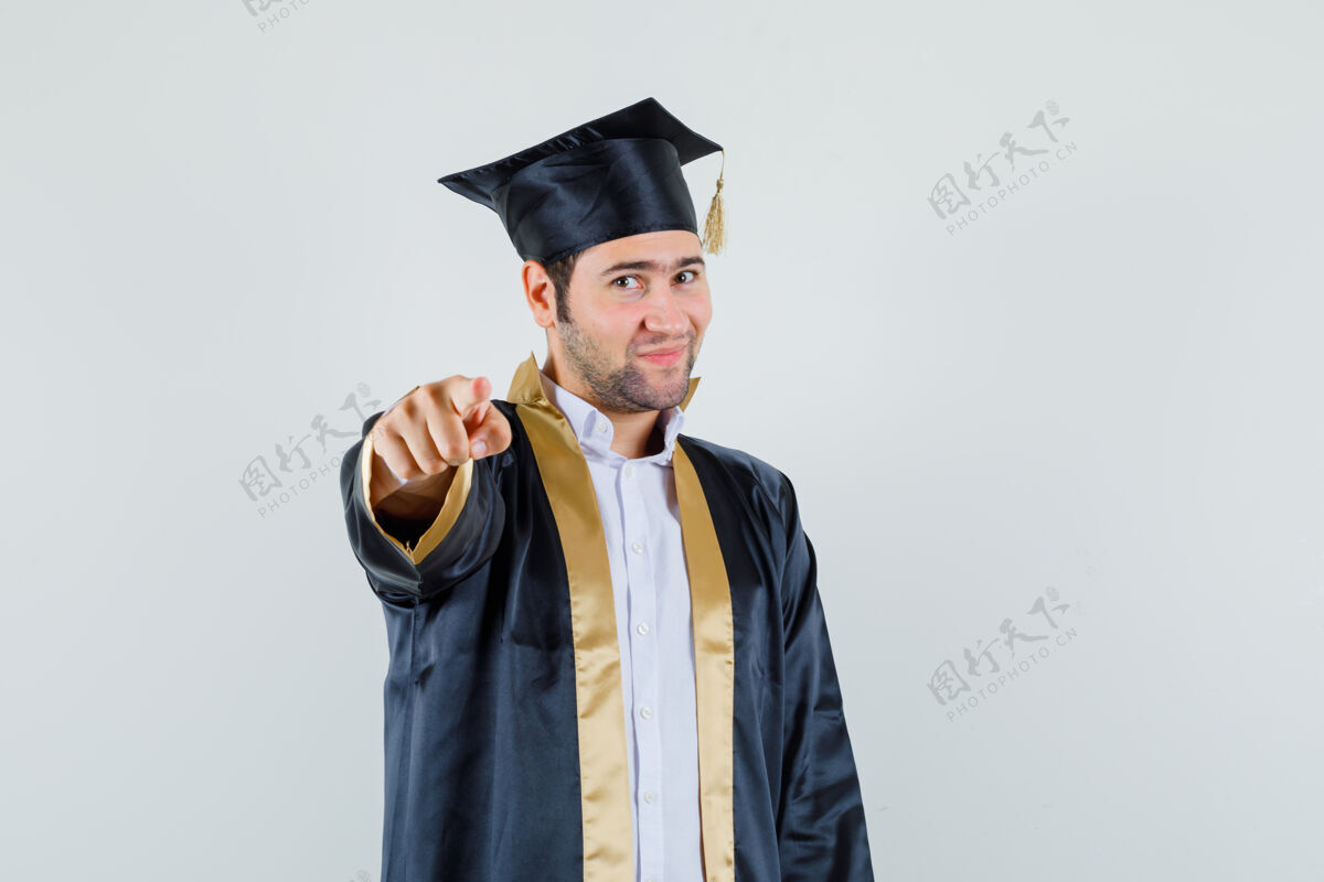 前面身着毕业制服的年轻人指着镜头 自信地看着前方成功制服欢呼