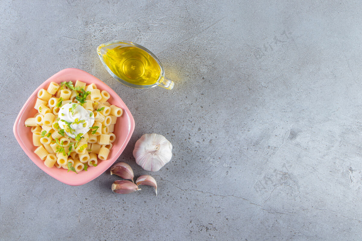 晚餐粉红色的一碗美味的煮熟面食 石头背景上有橄榄油大蒜佳肴一餐