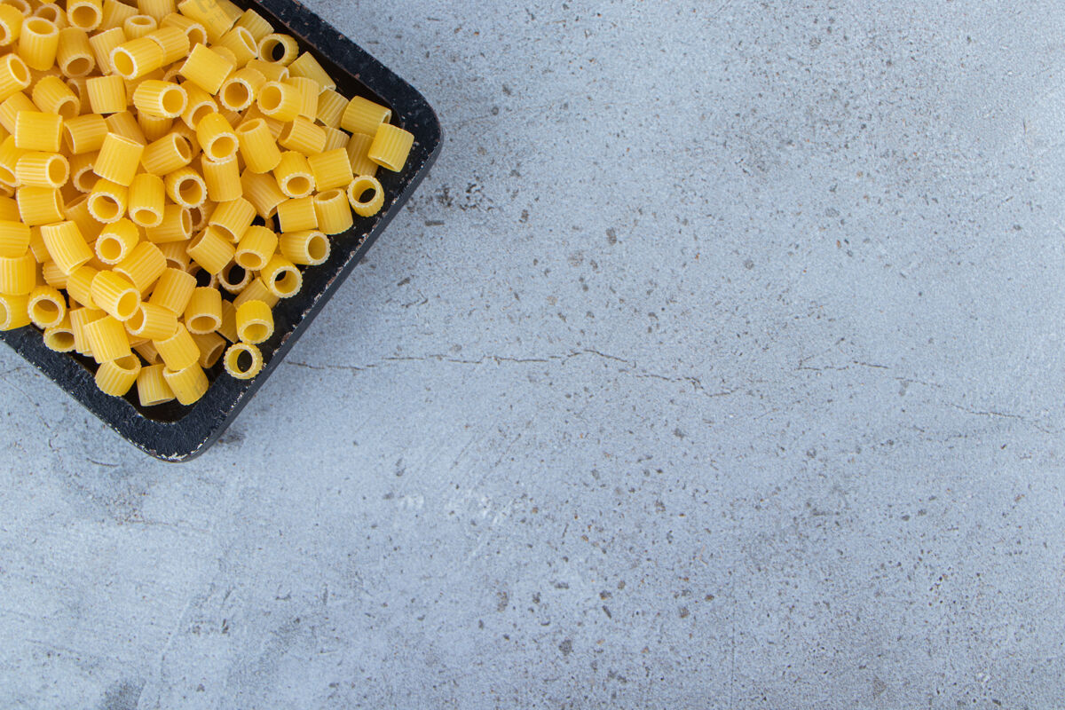 圆形一块黑木板 上面是生的干意大利面食物意大利食物面食
