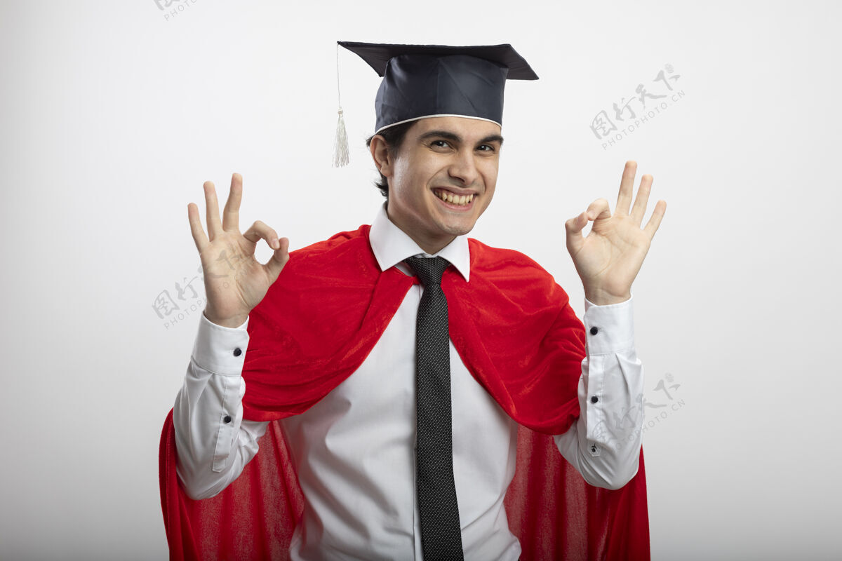 领带带着微笑的年轻超级英雄戴着领带和毕业帽 在白色背景上显示出良好的姿态手势男人年轻