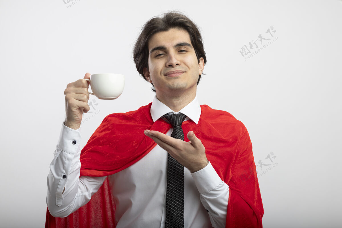 年轻年轻的超级英雄戴着领带 手拿着咖啡杯指着白色背景拿着杯子伙计