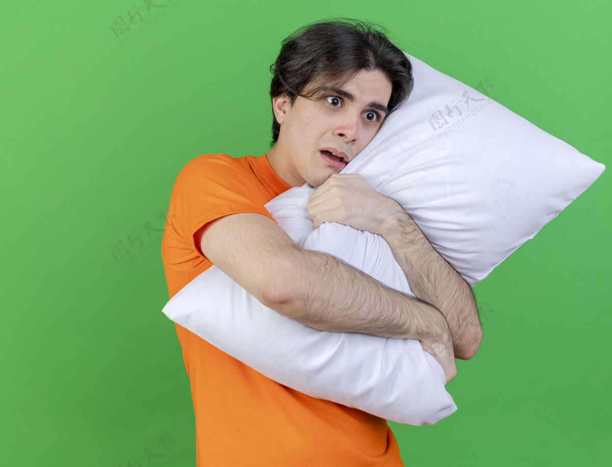 拥抱看着身边关心的年轻病夫抱着一个孤立在绿色背景上的枕头枕头年轻关心