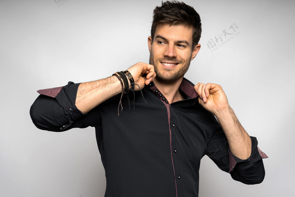 快乐快乐的年轻西班牙裔男子穿着黑色衬衫站在白色的墙上时尚成人青春