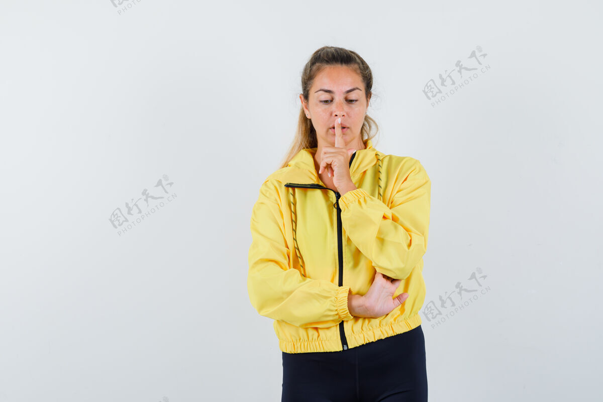 金发一个金发女人穿着黄色棒球服和黑色裤子表现出沉默的姿态 看起来很专注干净脸可爱