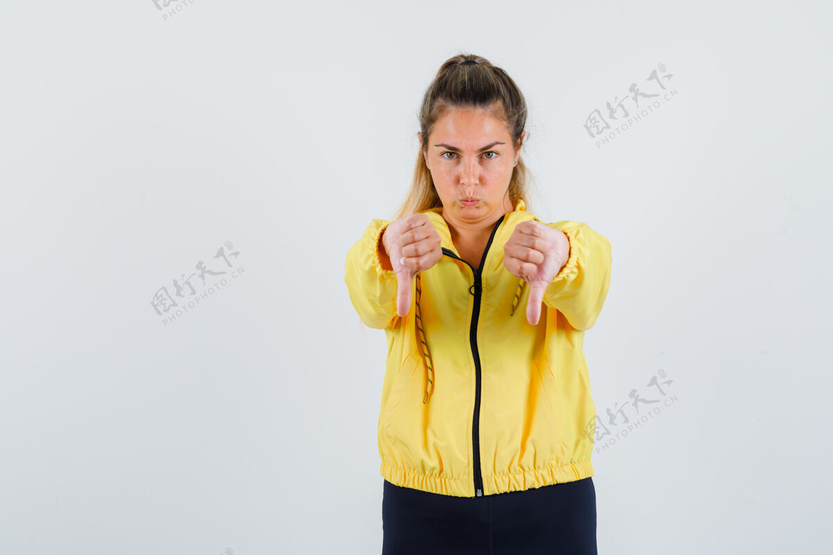 头发一个穿着黄色雨衣的年轻女人伸着大拇指 看上去很不高兴爱乐趣雨衣