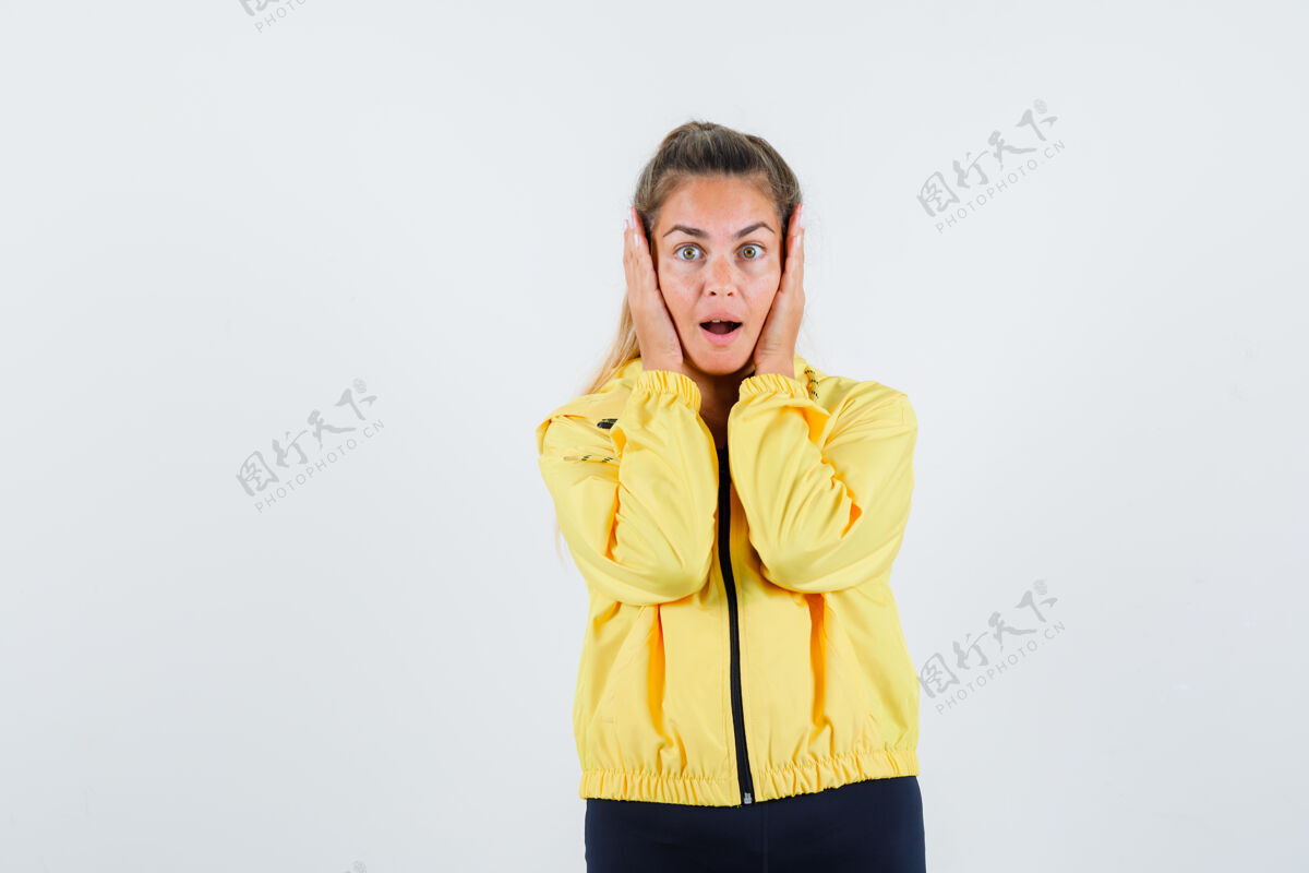 人穿着黄色雨衣的年轻女子双手紧握着脸 看上去很惊慌扣漂亮成人