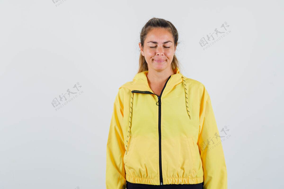 可爱一个穿着黄色雨衣的年轻女人闭上眼睛 满脸狐疑雨衣快乐肖像