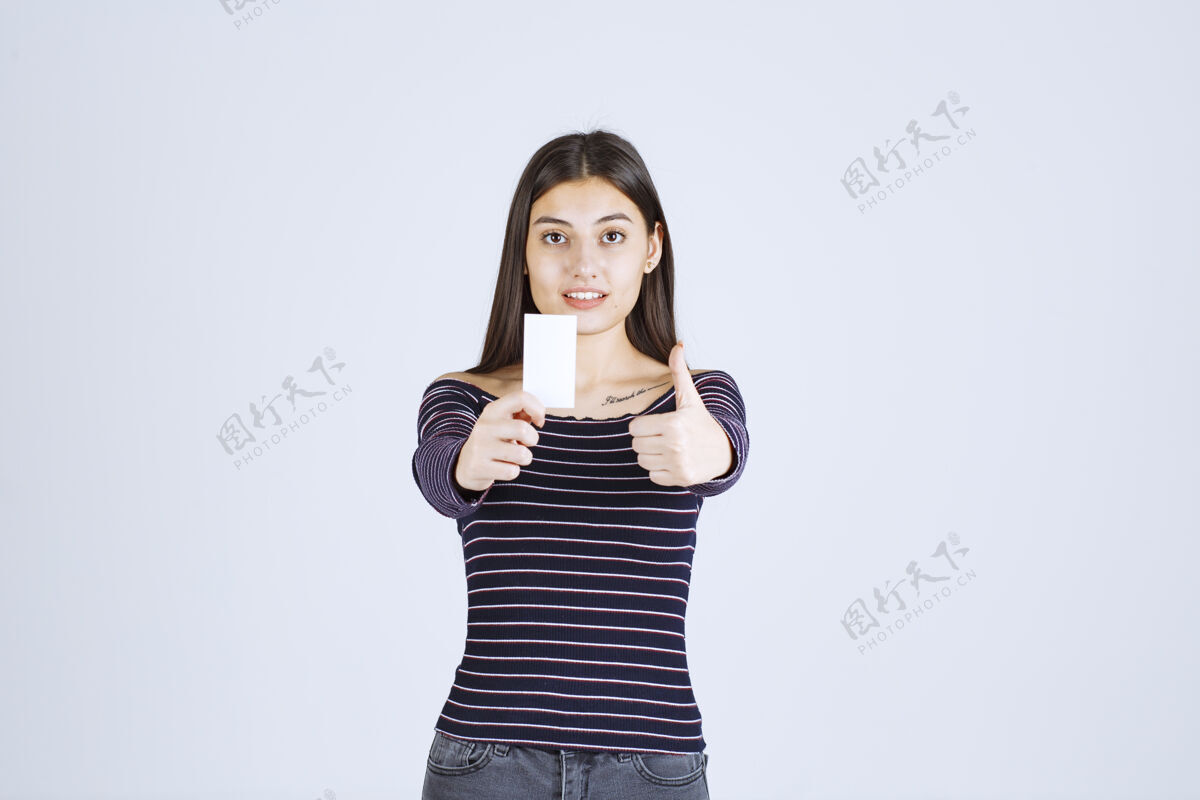 协议穿条纹衬衫的女孩拿着名片 举着拇指朝上的牌子休闲姿势女人