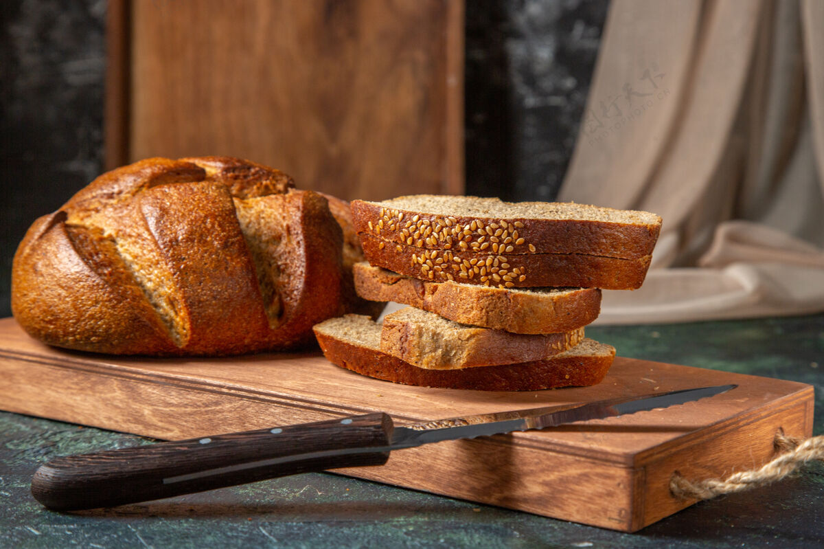 小麦整体俯视图和黑色面包切在棕色木砧板上的深色表面黑面包顶部面包房