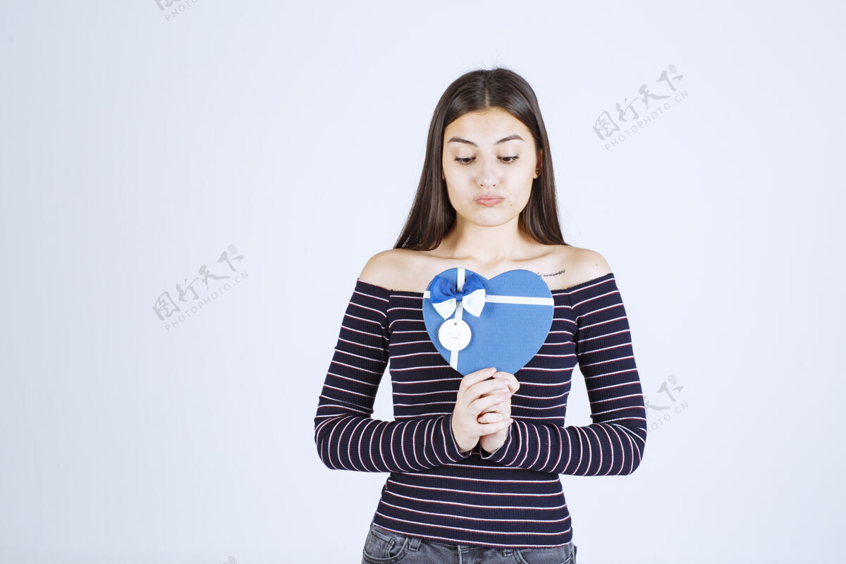 成人穿着条纹衬衫的女孩手里拿着一个蓝色心形礼盒 激动不已恐惧雇员人体模特