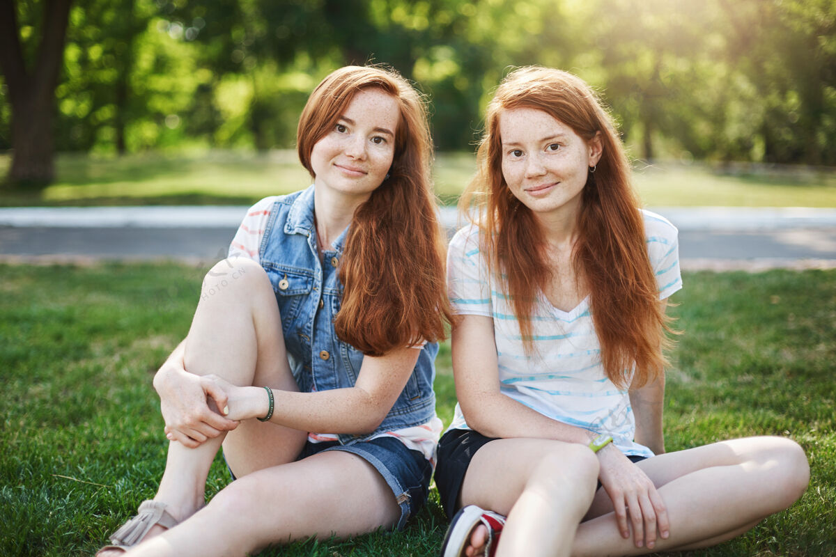 关心好看的两个女人 有着红发和雀斑 坐在大学校园旁的草地上 心寒友谊朋友身份