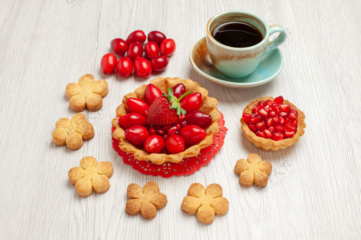 盘子正面图：带水果的小蛋糕和一杯茶放在白色桌面上水果甜点蛋糕盘子营养品热的