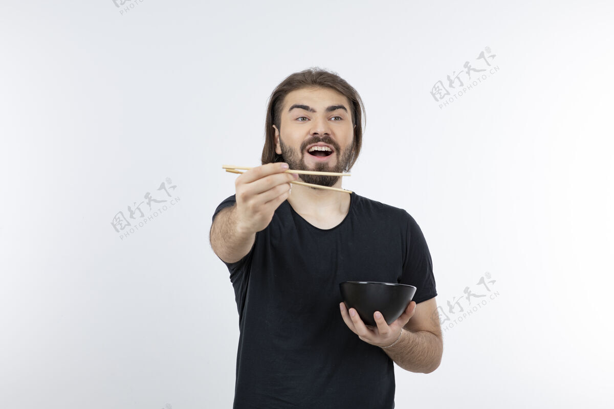 小伙子一个留胡子的男人拿着筷子在白色的墙上拿着碗男性站着模型