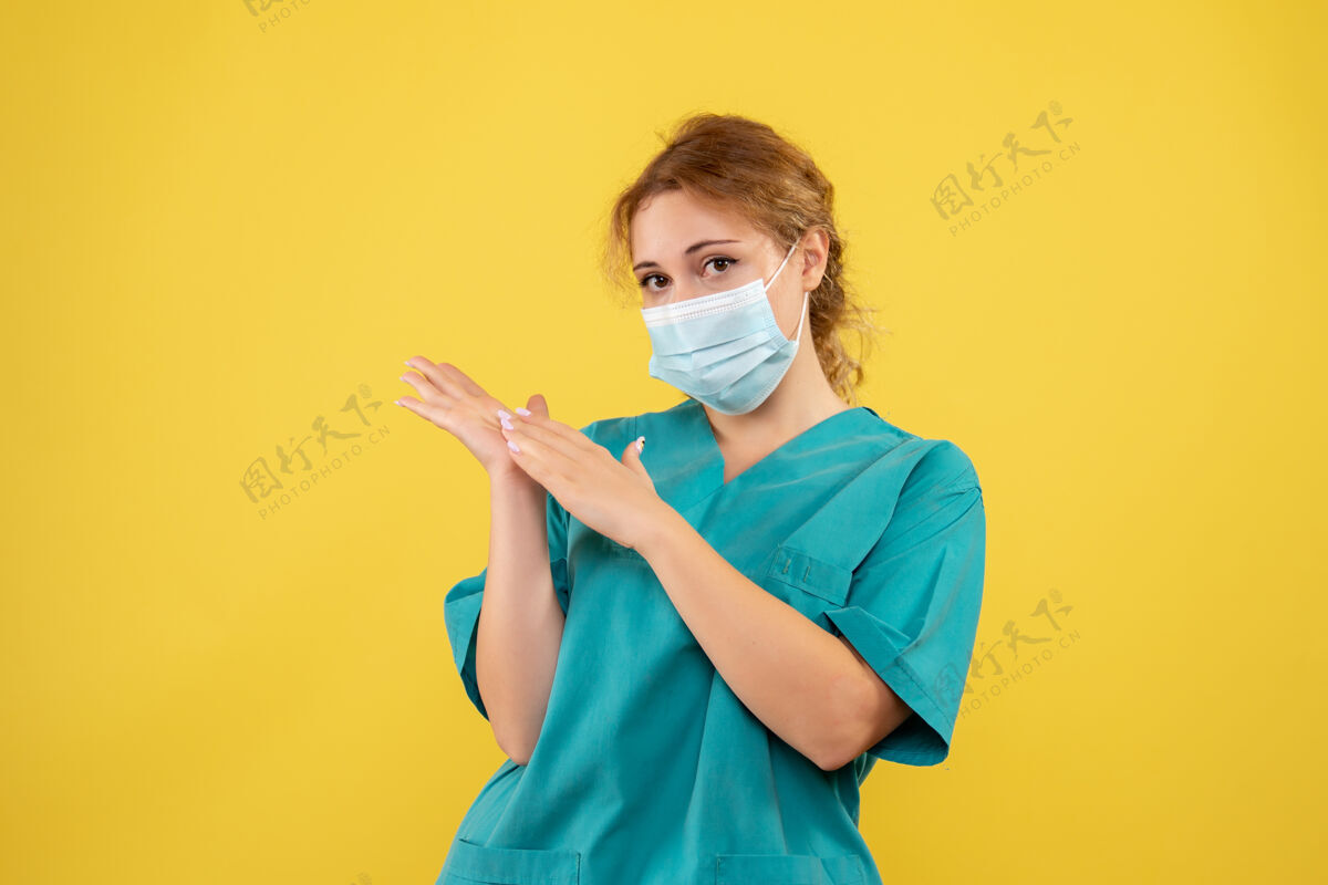 人黄墙上年轻女医生穿着医疗服 戴着无菌口罩的正面图西装医疗医院