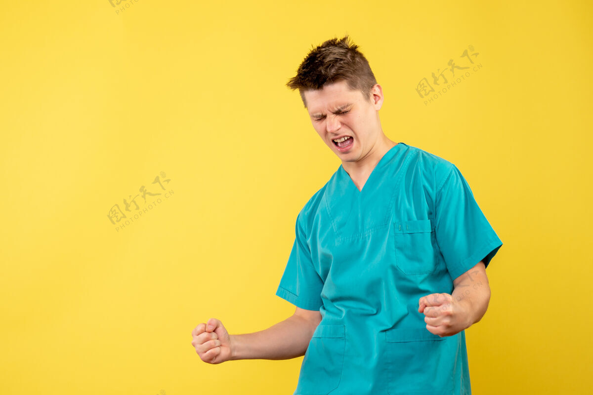 健康身着医疗服的男医生在黄色墙上欢呼雀跃的正面图医院男人快乐