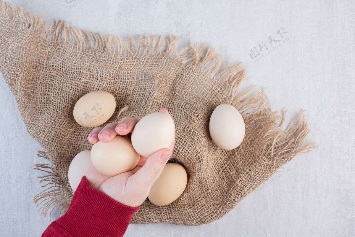 生的用手从大理石桌上的一块布上拿鸡蛋有机鸡蛋农产品