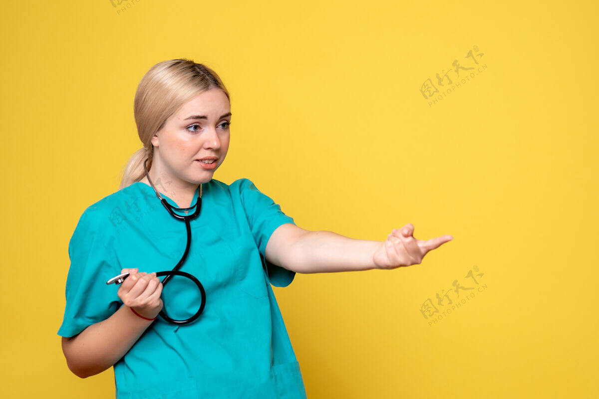 正面黄色墙壁上穿着带听诊器的医用衬衫的女医生的正视图衬衫病毒健康