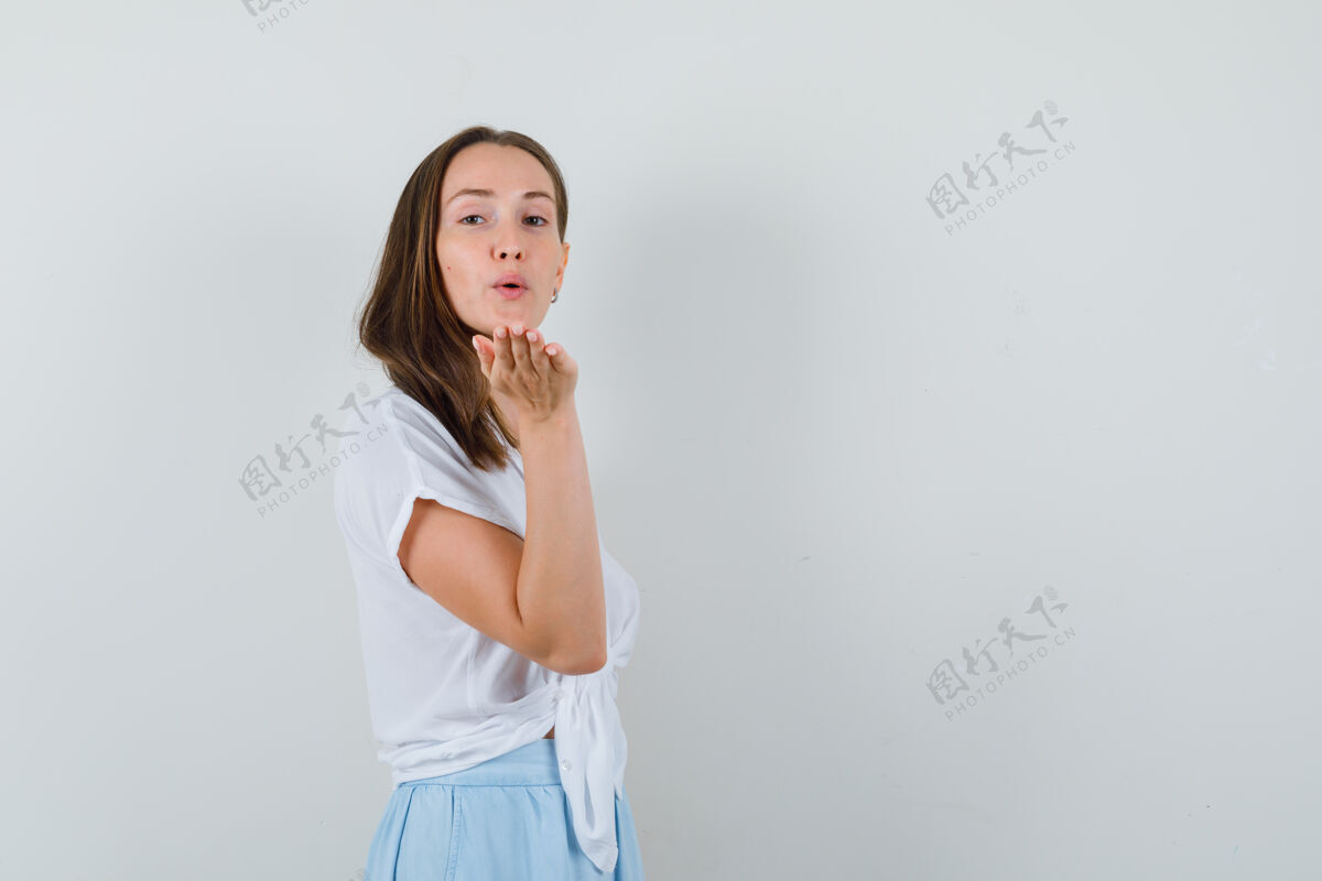 自然一个年轻的女人 穿着白衬衫和淡蓝色的裙子在前面送吻 看起来很迷人衬衫模特漂亮