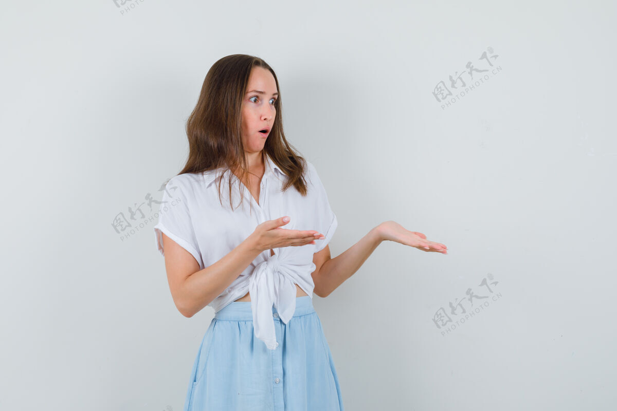 年轻这位年轻的女士摊开手掌 露出一件白衬衫 蓝裙子的东西 看上去目瞪口呆秀传播女人