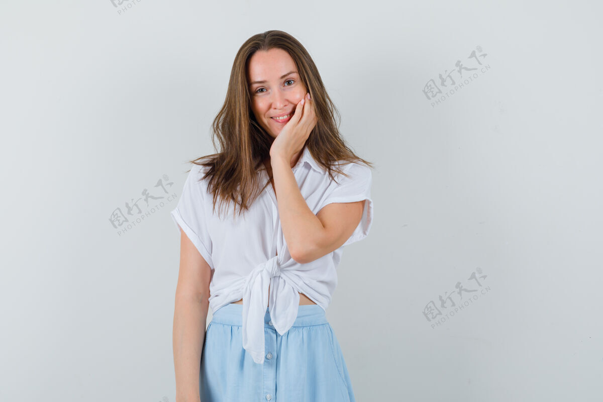 夏天一位穿着衬衫 裙子的年轻女士 手放在脸颊上 看起来很可爱年轻衬衫头发