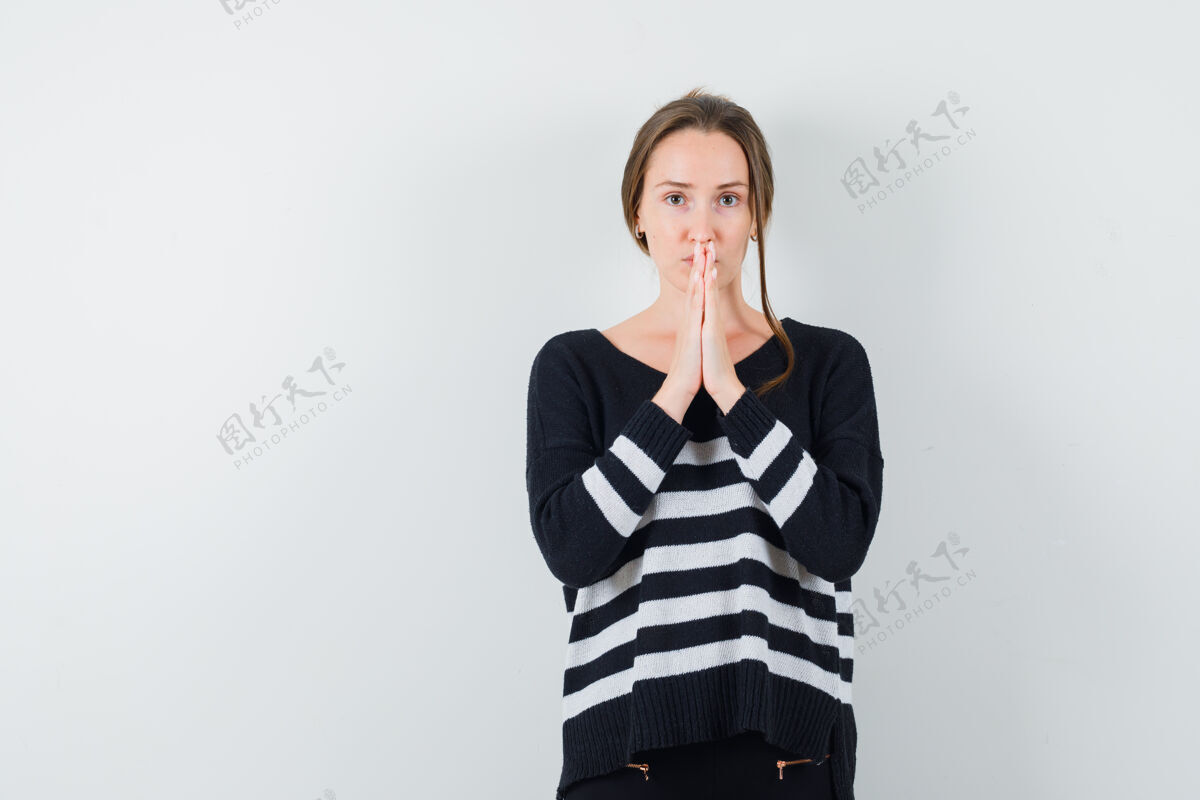 新鲜身穿黑色上衣和黑色裤子的年轻女子站在祈祷姿势 看起来很专注焦点时尚黑发