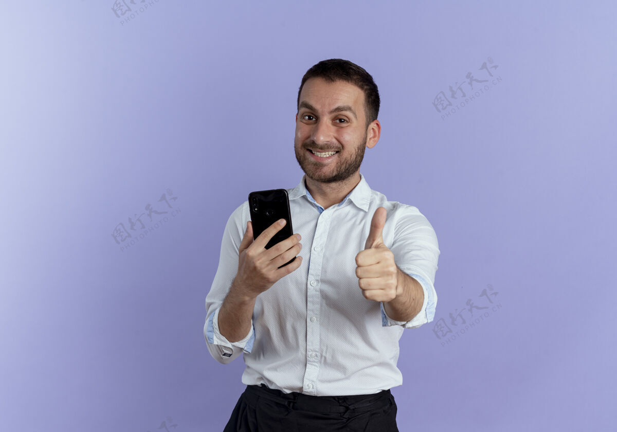 优雅笑容可掬的帅哥竖起大拇指 把电话孤零零地放在紫色的墙上人成人男人