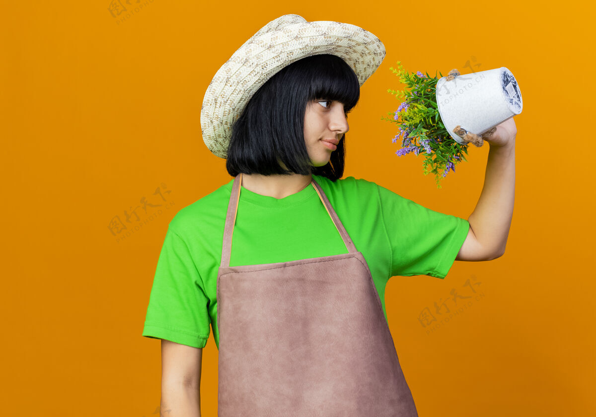 空间自信的年轻女园丁穿着制服 戴着园艺帽 拿着花盆看花儿帽子花盆女性