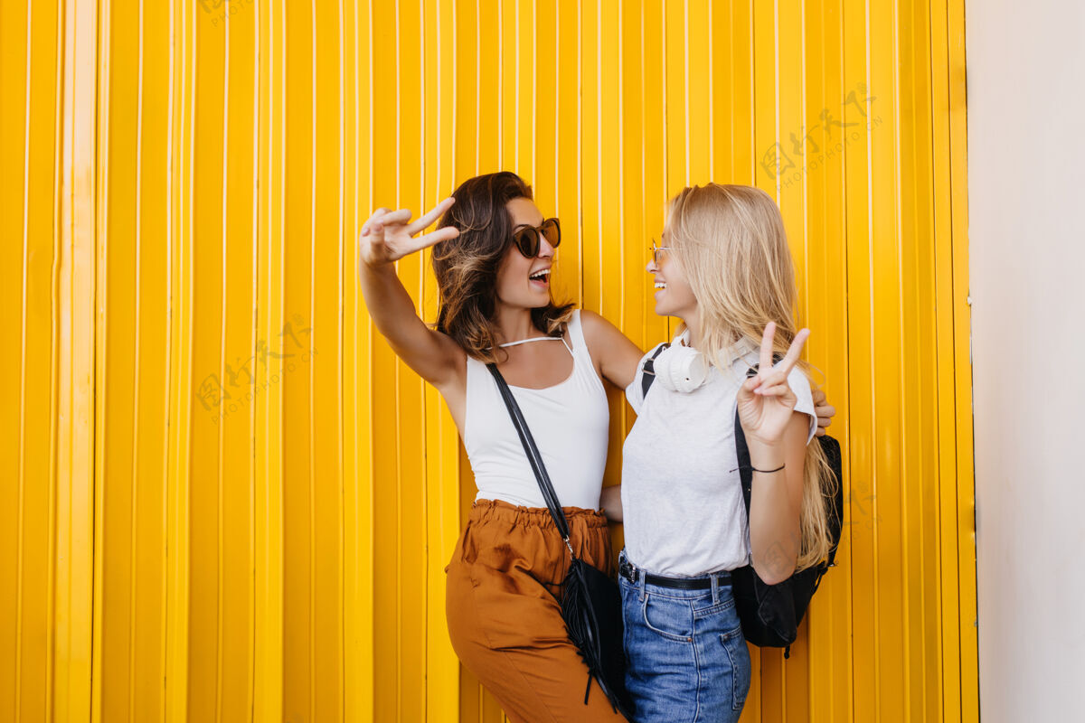 表情正面的白人女性在黄色背景上拍照时互相看着对方快乐女性欧洲
