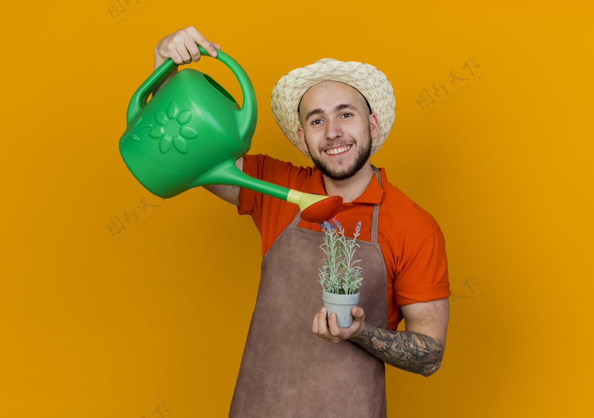 拿微笑的园丁戴着园艺帽拿着浇水罐假装给花盆里的植物浇水桔子假装花园