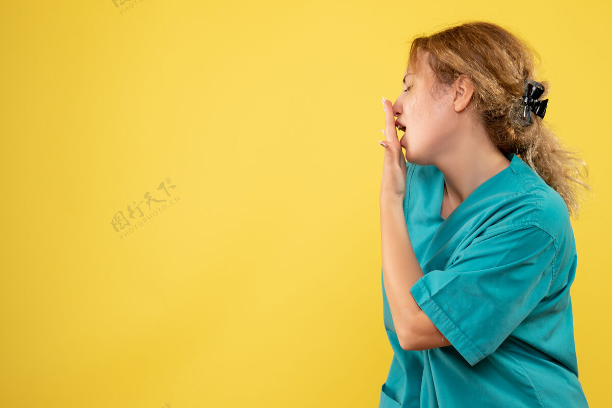 快乐黄墙上年轻女医生穿着医用衬衫打呵欠的正面图脸肖像成人