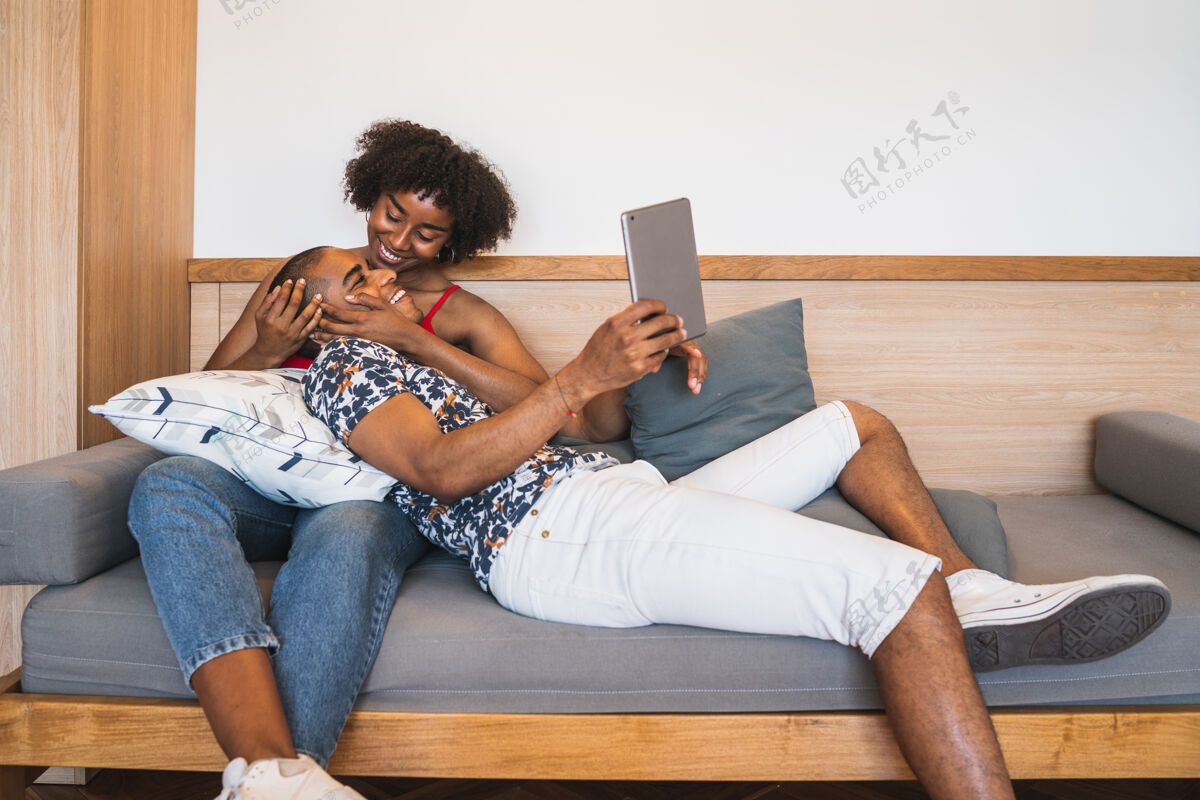 触摸板一对年轻的拉丁夫妇在家里用数字平板电脑自拍的照片沙发放松电脑