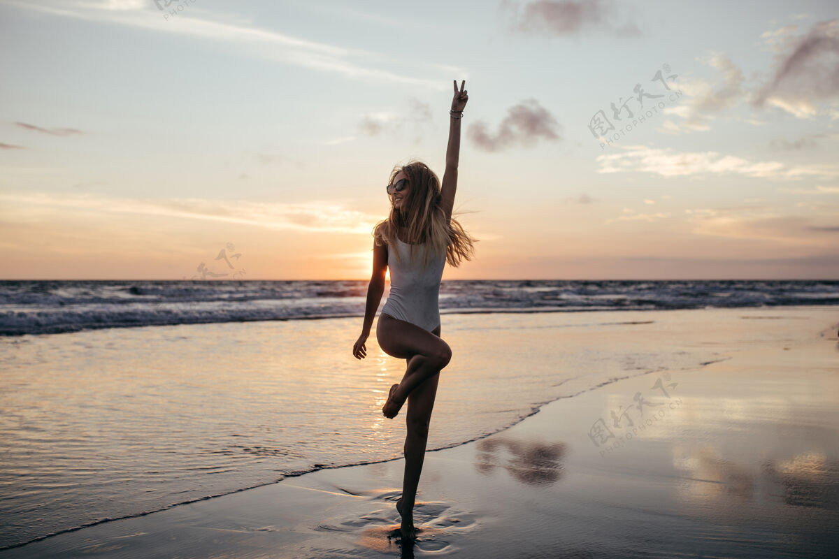 享受可爱苗条的女孩单腿站立在海边的全长镜头海洋灵感水