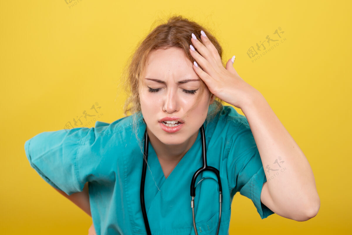 人黄色墙壁上穿着带听诊器的医用衬衫的女医生的正视图正面肖像医疗器械