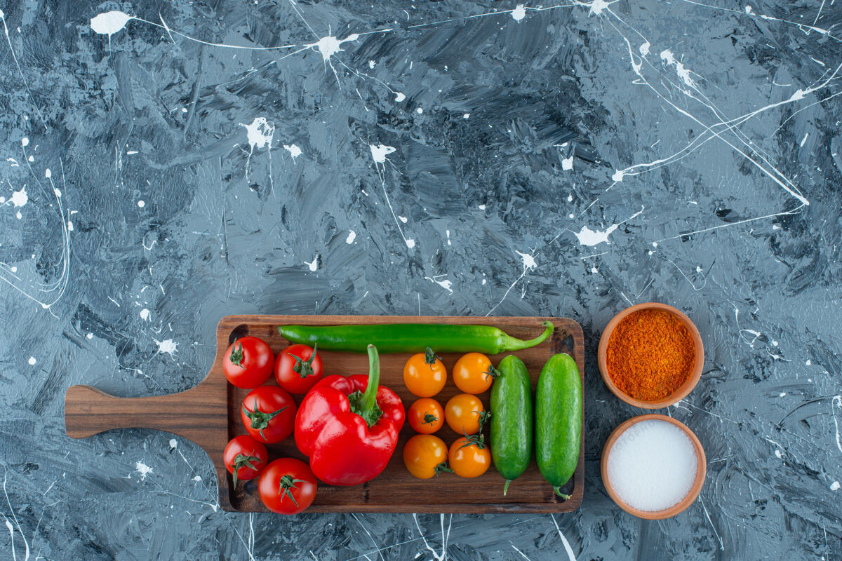 萝卜各种蔬菜放在一块木板上 旁边是盐和香料 背景是大理石蔬菜营养胡椒