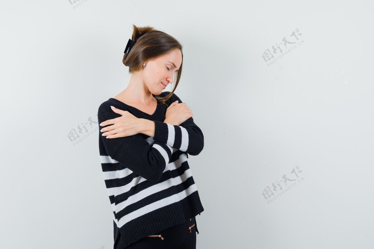 肖像穿着条纹针织衫和黑色裤子的年轻女子双臂交叉在胸前 看上去很放松女人新鲜胸部