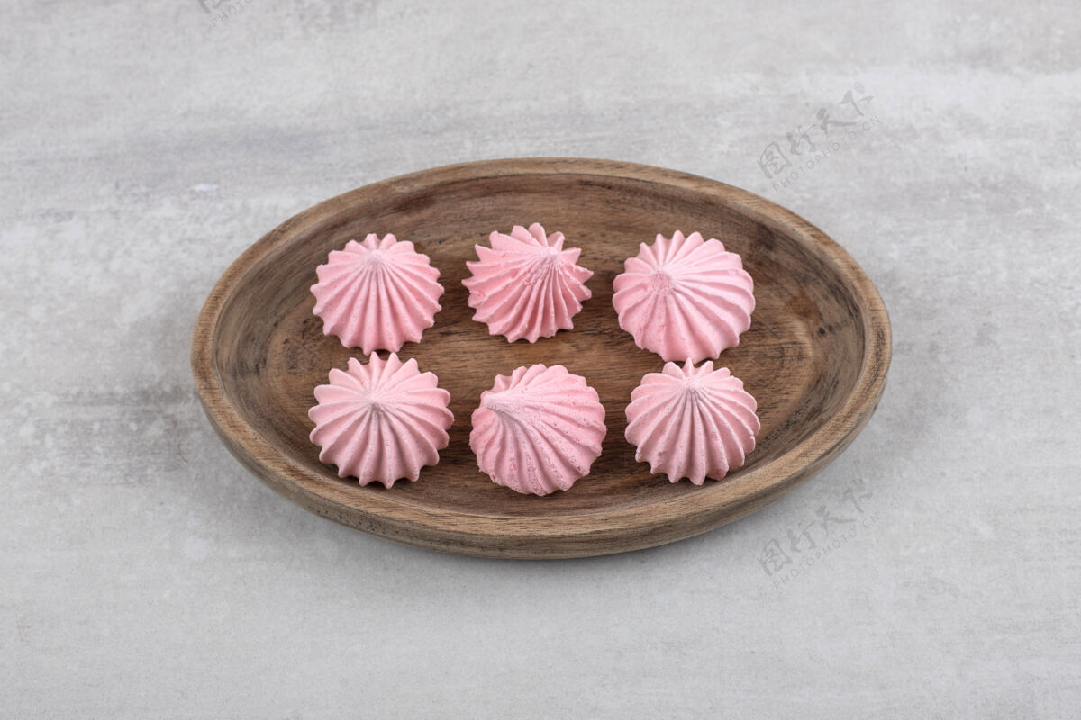 食材粉红色的蛋白酥皮放在木板上 放在大理石桌上配料糕点甜点