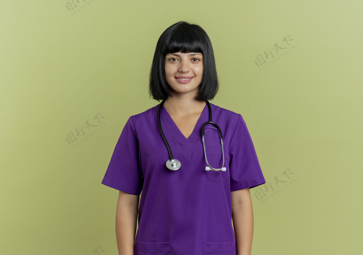 年轻微笑着的年轻黑发女医生身着制服 手持听诊器 站在橄榄绿背景上 留有复印空间黑发制服奥利弗