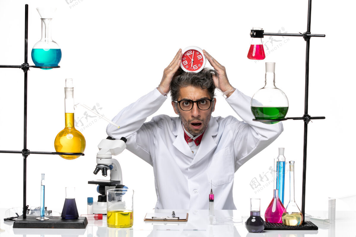 专业前视图身穿医疗服的男科学家拿着白色背景上的时钟化学冠状病毒实验室健康医院实验室病毒