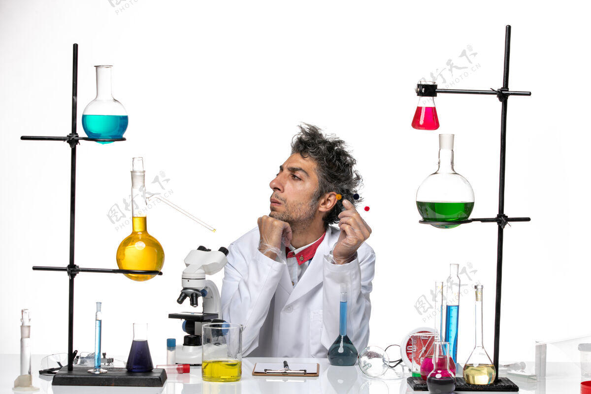 实验室正面图：男性科学家拿着样品在桌子前 白色背景上有解决方案冠状病毒健康实验室covid手持专业人员实验室