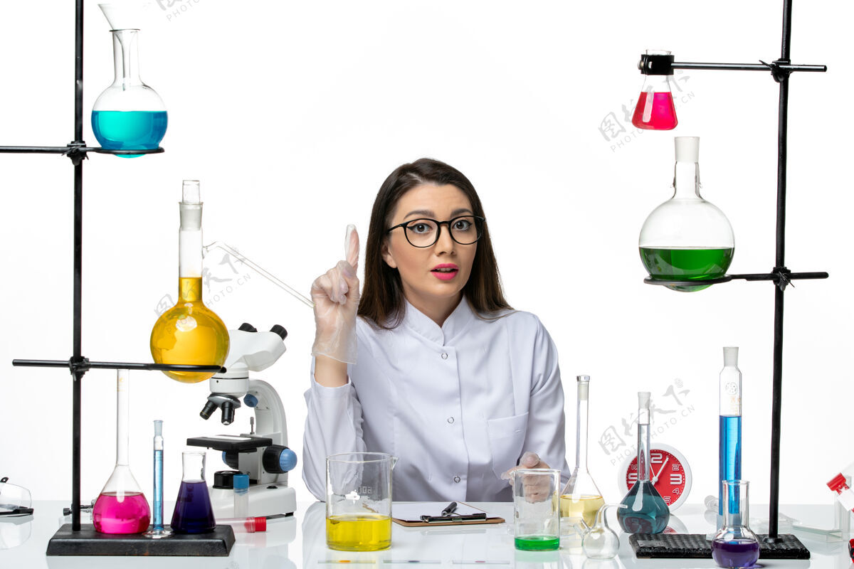 罐子前视图穿着白色医疗服的女化学家正坐在浅白背景上拿着解决方案科学大流行实验室病毒冠状病毒人医学容器