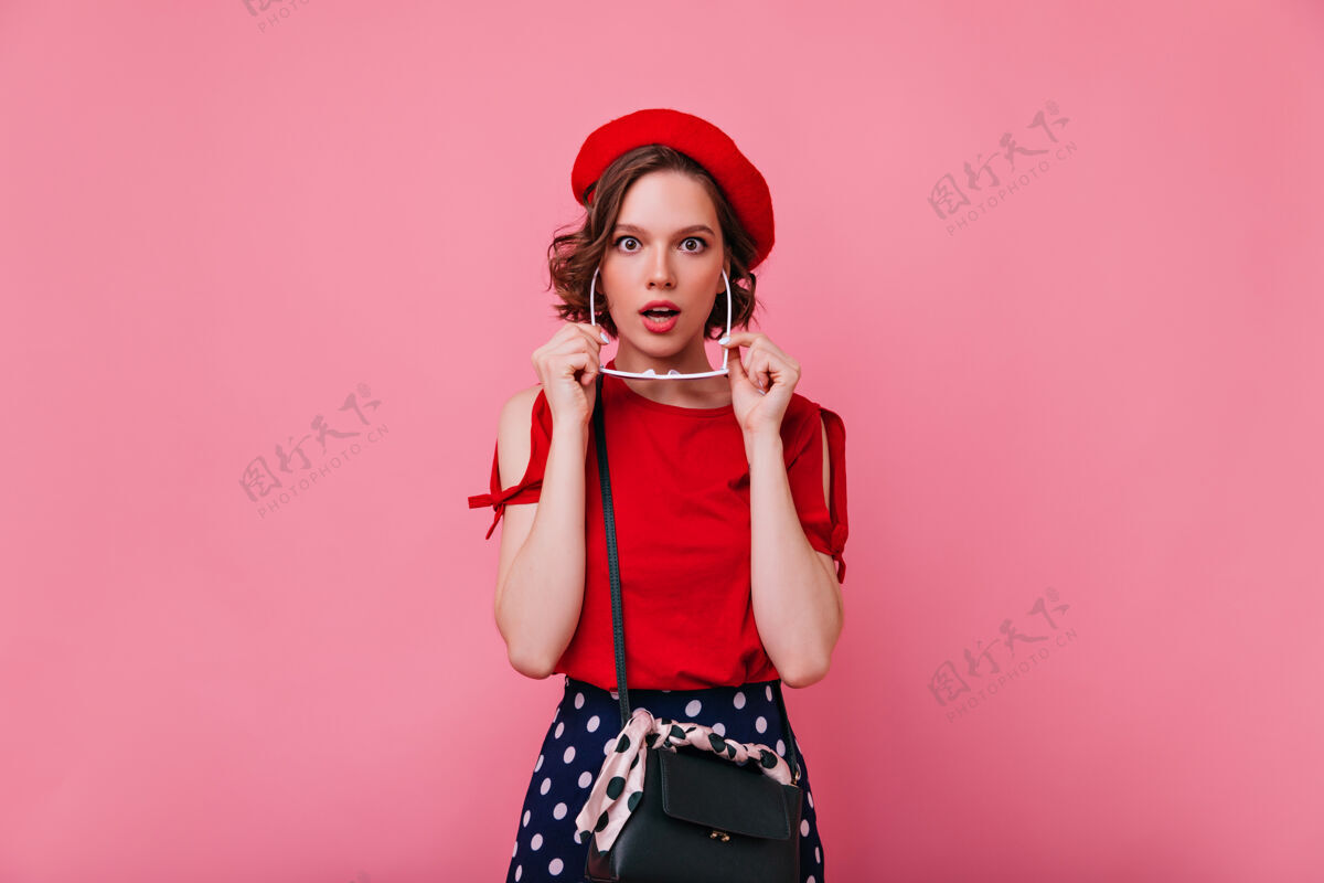 大人浪漫的法国女士摆出惊讶的表情室内拍摄的红色贝雷帽可爱的卷发女子EmotationsFunCute