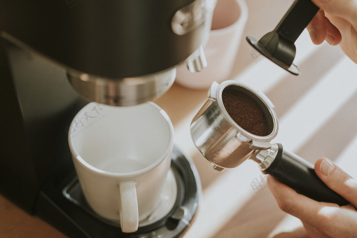 木头桌子咖啡师在咖啡机的过滤器里压榨磨碎的咖啡咖啡渣咖啡店马克杯