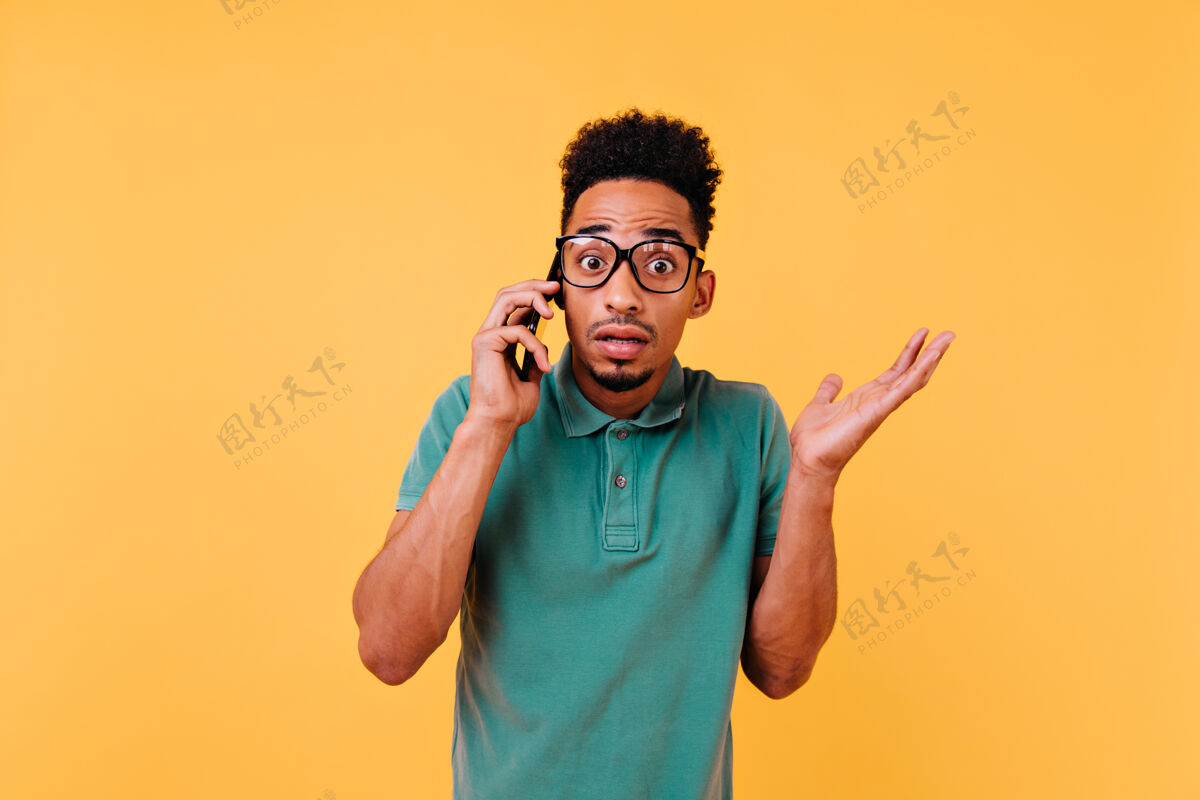 微笑一个戴着大眼镜的非洲男人在讲电话一个情绪激动的卷发男人和智能手机合影的肖像休息休闲男人