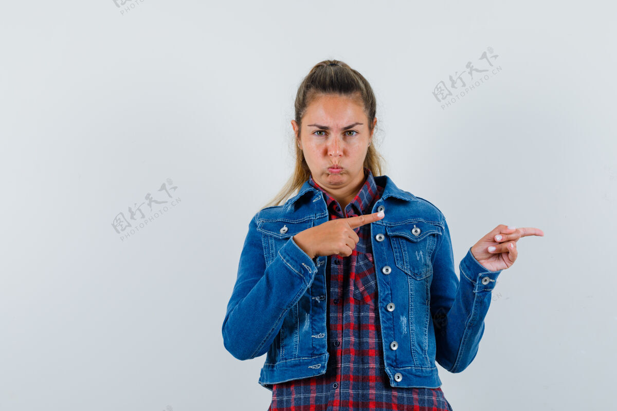 人穿着衬衫 夹克衫的年轻女子指着一边 看上去很有恶意 正对着前方女人一个成人