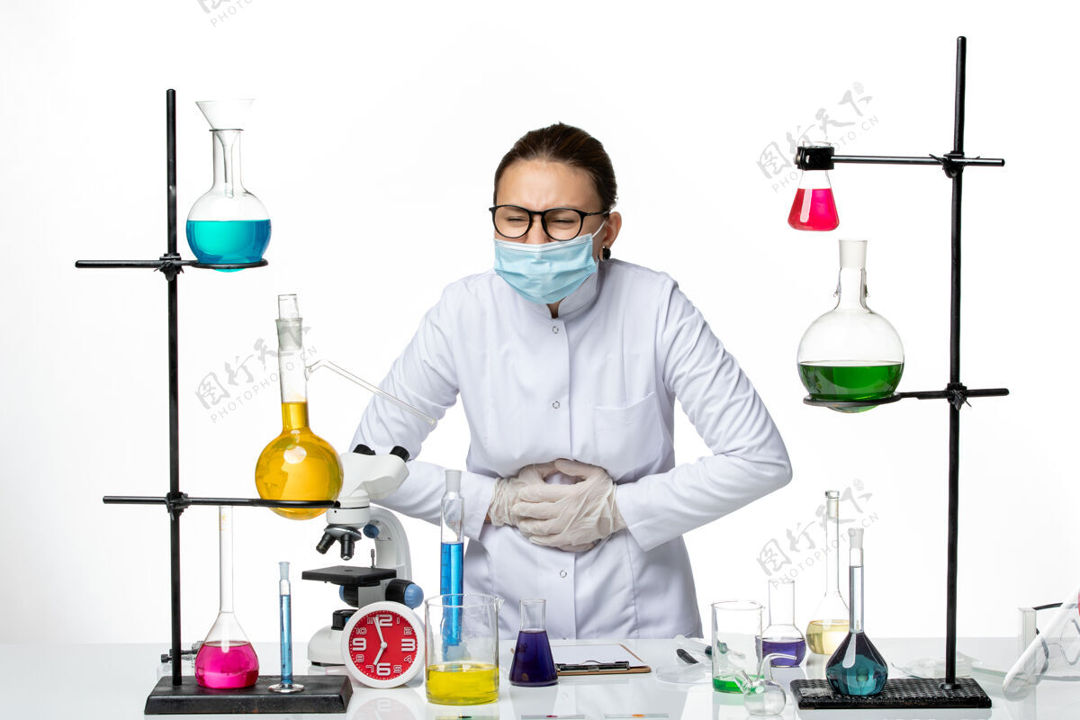 病毒正面图白色背景病毒化学实验室covid-splash上穿着医疗服带口罩胃痛的女化学家医生专业外套