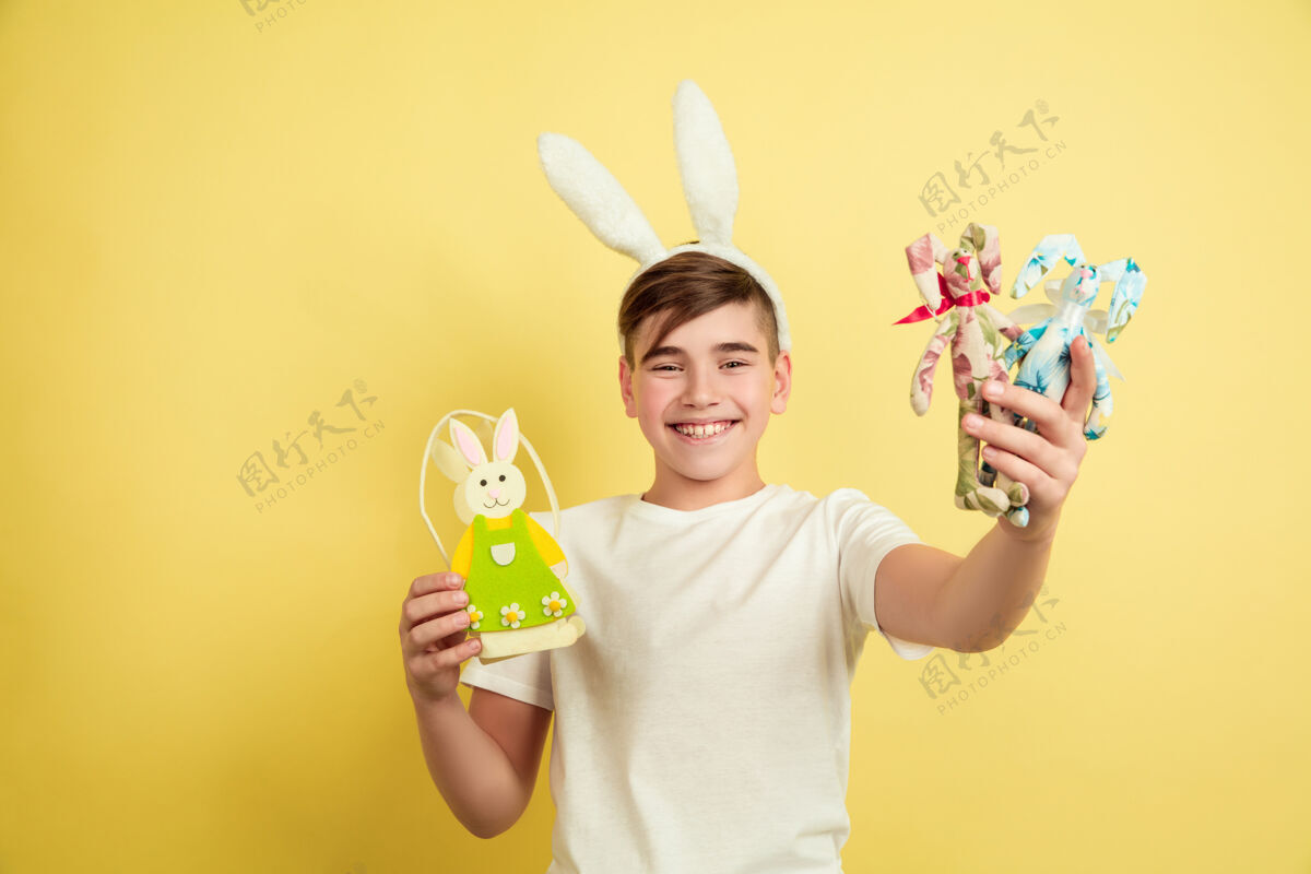 肖像白人男孩作为复活节兔子在黄色工作室背景男孩人类有趣